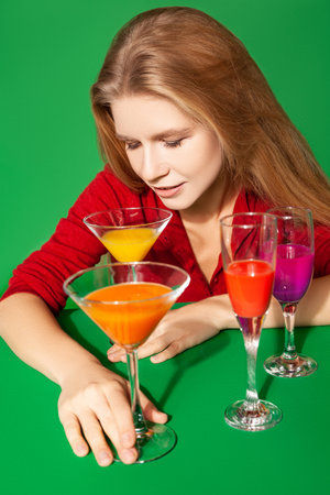 Young female with colorful alcohol drinks on green backgroundの写真素材