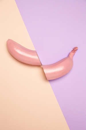 Halved unpeeled pink banana placed on two color surfaceの写真素材
