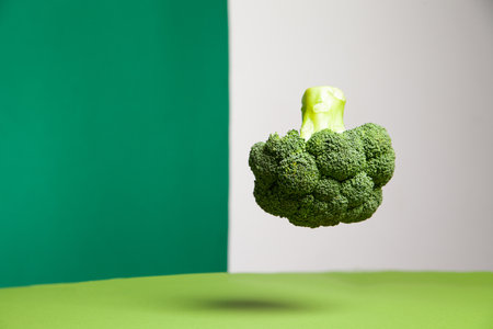Tasty fresh broccoli head levitating in green studioの写真素材