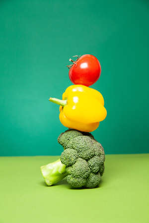 Ripe fresh colorful broccoli bell pepper and tomato against green backgroundの写真素材