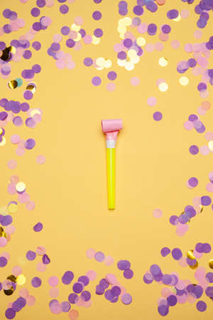Party horn and scattered shiny confetti on orange backgroundの写真素材