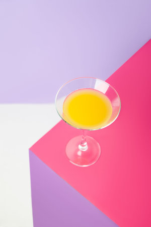 Glass of cocktail with lemon on colorful table