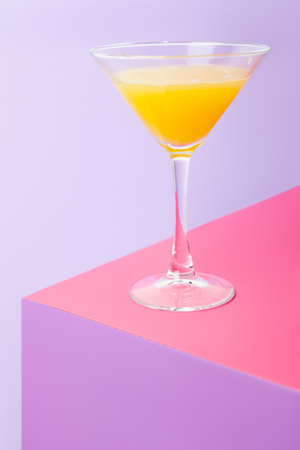 Glass of cocktail with lemon on colorful tableの写真素材
