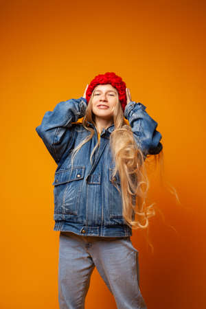 Smiling young woman in warm clothes against bright orange backgroundの写真素材