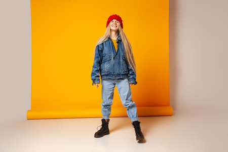 Cheerful trendy woman in denim outfit and hat having fun in studioの写真素材