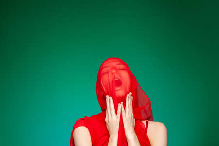 Suffering woman with red cloth on faceの写真素材