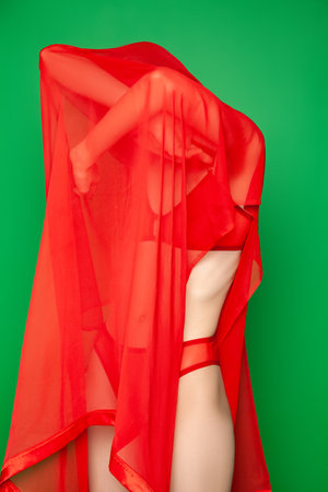 Dreamy woman under red veil against green backgroundの写真素材