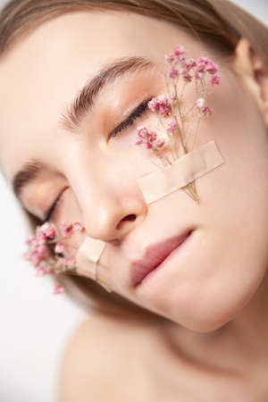Tender woman with healthy skin and flowers on faceの写真素材