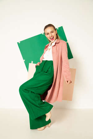 Happy fashionable woman in green pants in studio with white backgroundの写真素材