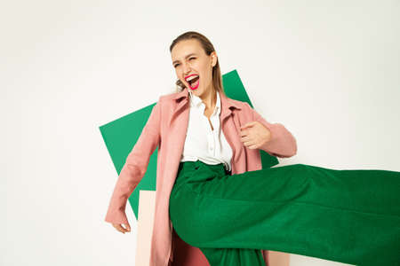 Happy fashionable woman in green pants in studio with white backgroundの写真素材