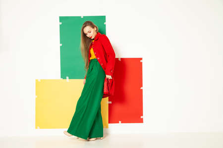 Happy fashionable woman in green pants in studio with white backgroundの写真素材