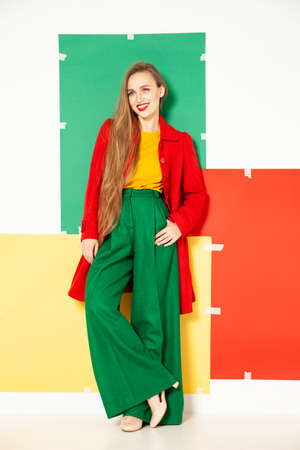 Happy fashionable woman in green pants in studio with white backgroundの写真素材