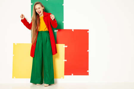 Happy fashionable woman in green pants in studio with white backgroundの写真素材