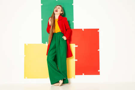 Happy fashionable woman in green pants in studio with white backgroundの写真素材