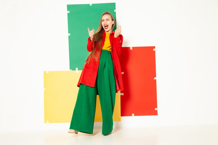 Happy fashionable woman in green pants in studio with white backgroundの写真素材