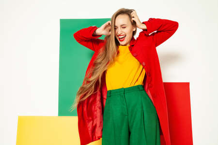 Happy stylish woman in colorful wear having fun in studioの写真素材