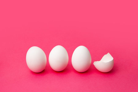 White eggs near broken shell on pink table