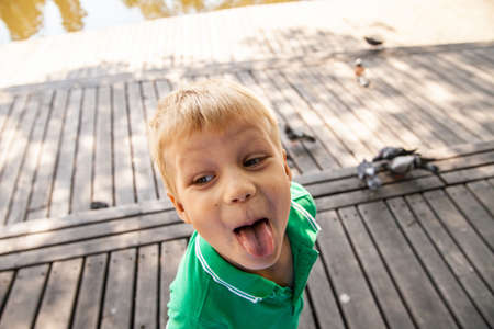 Funny little kid showing tongue in parkの写真素材