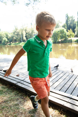 Little boy playing near lake in parkの写真素材