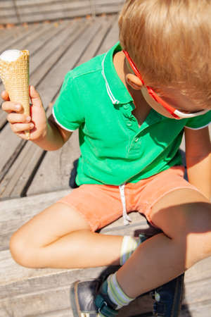 Funny little child in sunglasses eating ice cream in parkの写真素材