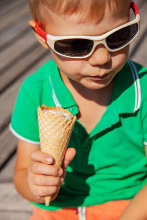 Happy child in sunglasses with ice cream coneの写真素材