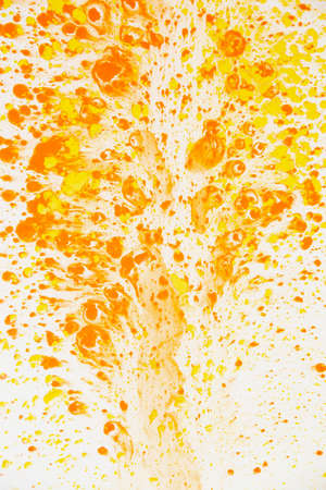 White wall with chaotic orange paint dropsの写真素材