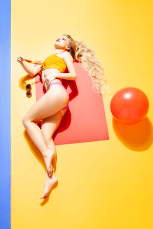 Slim woman in bikini lying on floor in studioの写真素材