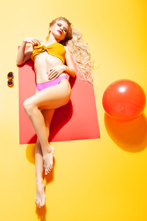 Slim woman in bikini lying on floor in studioの写真素材