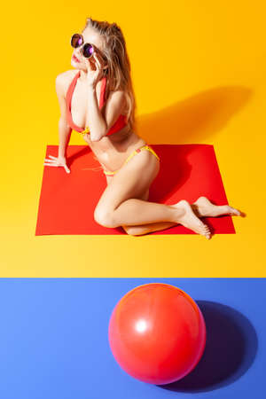 Slender woman in bikini sitting on floor in studioの写真素材