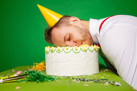 Funny man lying with face in birthday cake