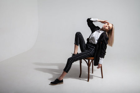 Full body young female model in trendy smart casual clothes touching head and leaning back while...