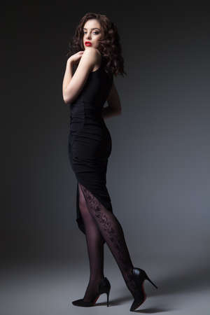 Gorgeous young woman posing in black dress and looking at camera.の写真素材