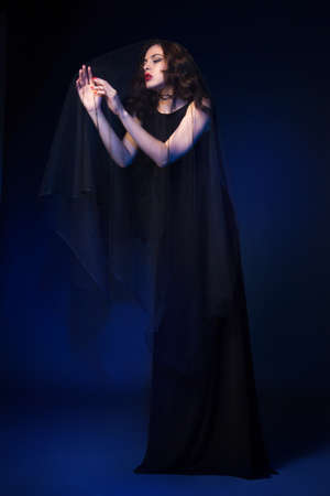 Attractive female wearing black dress posing with eyes closed. Vertical studio shot.の写真素材