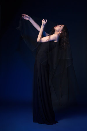 Attractive female wearing black dress posing with eyes closed. Vertical studio shot.の写真素材