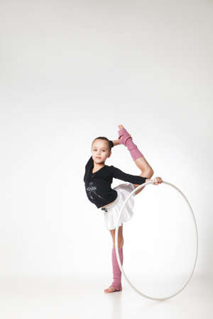 Portrait of a pretty little girl doing gymnastics over white backgroundの写真素材