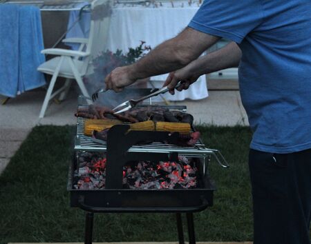coals burning in a barbecue with vegetables and meat on the grillの写真素材