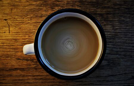 stir latte in a black and white cup in a wooden backgroundの写真素材