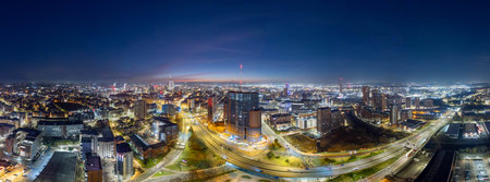 A breathtaking aerial panorama showcasing the illuminated skyline of Leeds city center under a stunning early morning dawn. The image highlights the city's vibrant urban landscape, including roads and developments.の写真素材