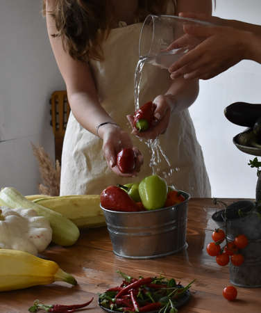 Woman in the farm house washing vegetables under running water pepper hot pepper fresh zucchini cherry tomatoの写真素材