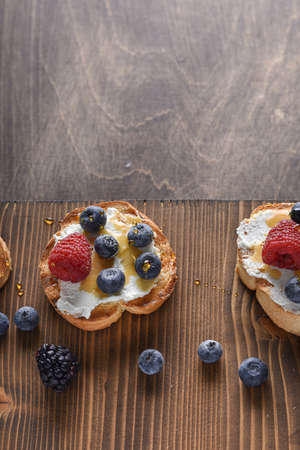 Home breakfast toasts with goat cheese and berries jam on the wooden table. horizontal top view. copy spaceの写真素材