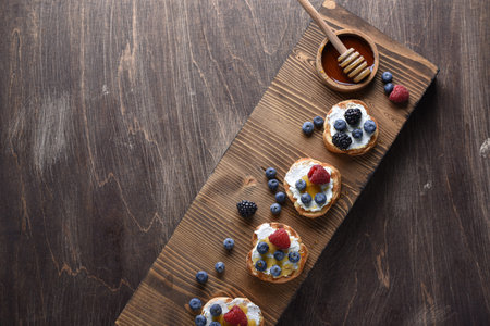 Home breakfast toasts with goat cheese and berries jam on the wooden table. horizontal top view. copy spaceの写真素材