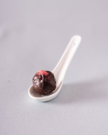 dark chocolate truffle on white spoon. close up. Verticalの写真素材