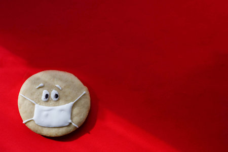 homemade sugar round cookies on red background, face with medical mask, place for inscription