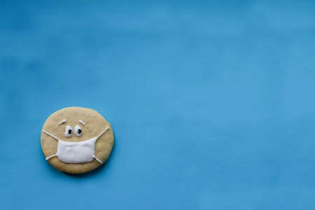 round sugar cookies in a medical mask on a blue background, place for an inscriptionの写真素材