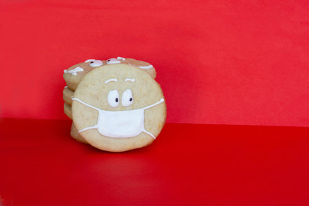 sugar cookie on a red background with a painted face in a medical mask, quarantine, covid, warning, Copyspaceの写真素材