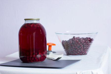 cherry compote in a glass jar for the winter, preparing food for storage, cherries in a transparent...