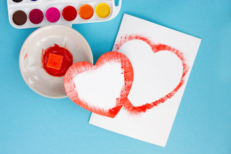 happy valentines day, girls hands make a greeting card for the holiday, instruction, step by step, DYI step seven two ready-made openings for congratulations in the form of a heartの写真素材