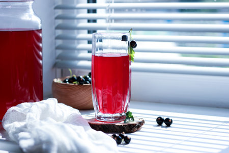 black currant juice with a glass glass on the window in the shade of the blinds, berries, summer soft drinks, healthy food.の写真素材