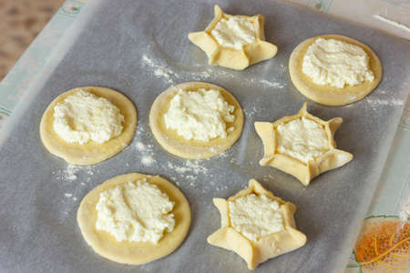 a circle of dough with cottage cheese filling on the table, cooking cheesecakes with cottage cheese.の写真素材