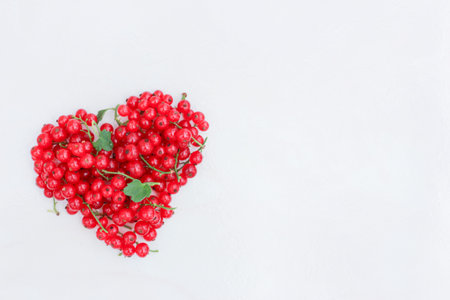 heart laid out of red currant berries on a light background, space for textの写真素材